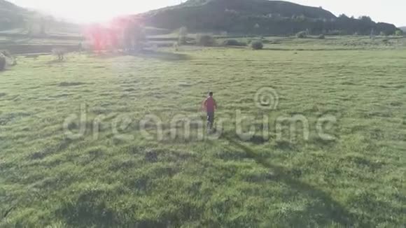 在绿油油的草地上飞过运动员在山上日落平的颜色视频的预览图