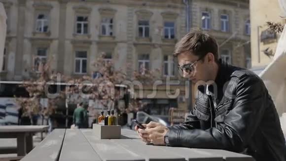 年轻人在智能手机上发短信在咖啡馆里使用智能手表年轻的高加索人通过电话从网上购买商品视频的预览图