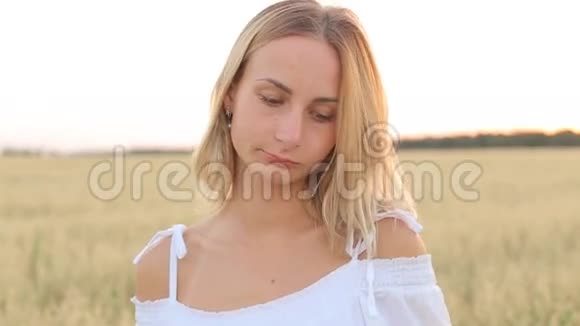 一个悲伤的年轻女子站在田野里看着镜头视频的预览图