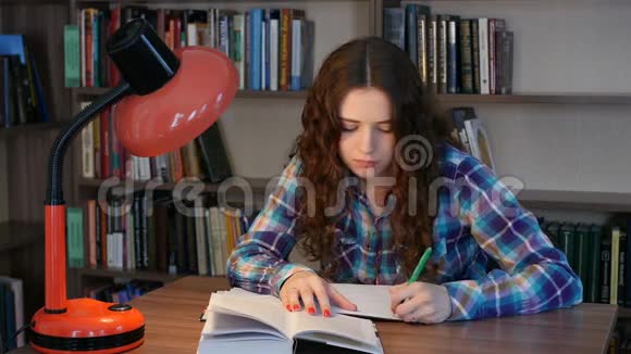 一个学生坐在图书馆的桌子旁在笔记本上写字4K视频的预览图