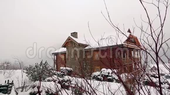 大雪时山村的木屋背景是针叶林落在原木上的雪视频的预览图