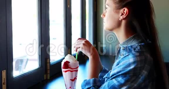 快乐的女人一边喝奶昔一边透过窗户看着视频的预览图