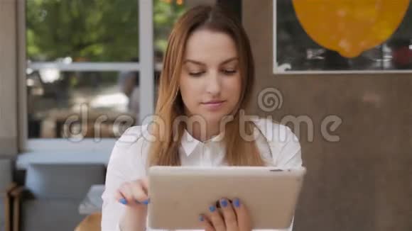 年轻漂亮的商务女性在户外咖啡厅午休时使用平板电脑视频的预览图