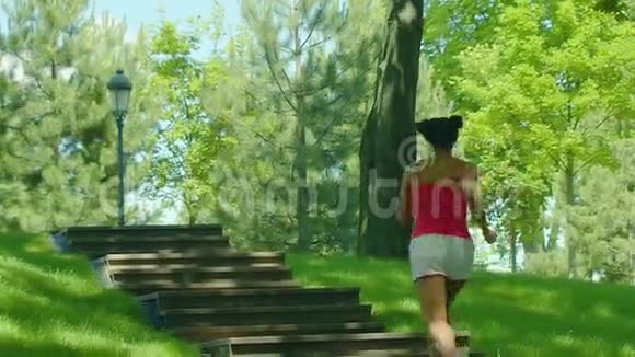 女人缓慢地跑上楼梯在公园楼梯上奔跑的女孩视频的预览图