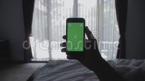 合上躺在床上的年轻人手里拿着智能手机绿色屏幕彩色键绿色屏幕分享真实的社交视频的预览图