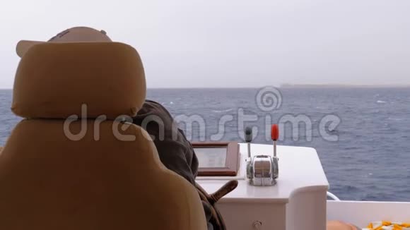 坐在游艇方向盘上的船长船长控制游艇视频的预览图
