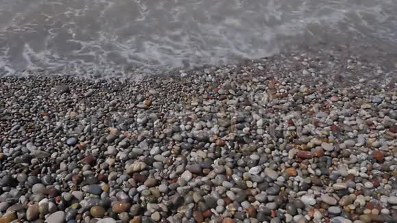 从波浪泡沫和彩色石头的上方可以看到卵石滩视频的预览图