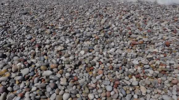 从波浪泡沫和彩色石头的上方可以看到卵石滩视频的预览图