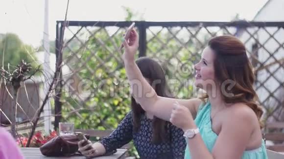 年轻女孩坐在餐厅的露台上智能手机孕妇假期视频的预览图