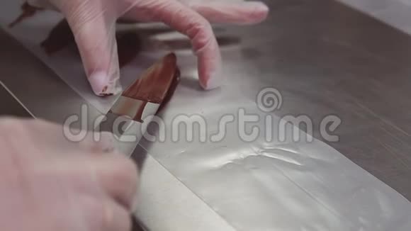 女性甜点厨师手戴塑料手套把巧克力放在烹饪条上视频的预览图