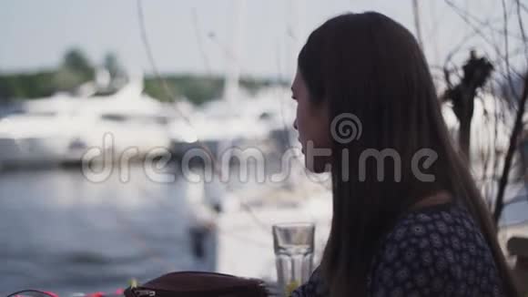 坐在海滨餐厅露台上的年轻女孩和别人说话视频的预览图