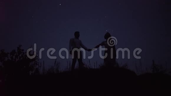 山里的一对浪漫的情侣正把星星放在背景上夜间射击视频的预览图