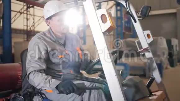 一个人驾驶叉车穿过工厂的仓库司机穿制服和防护头盔的概念视频的预览图