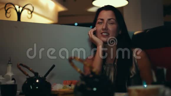 布鲁内特女孩坐在寿司店的桌子旁在笑与某人交谈视频的预览图