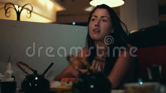 布鲁内特小姐坐在寿司店的桌子旁与别人交流视频的预览图