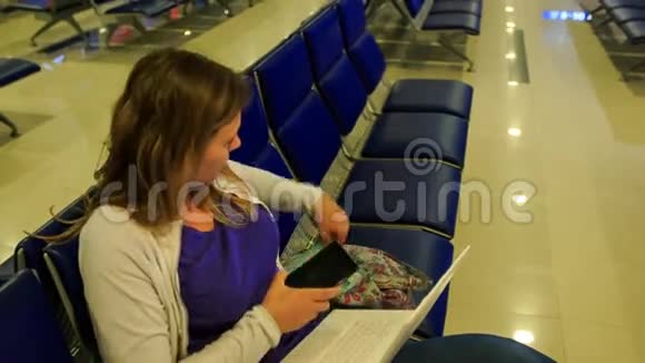 金发女孩在机场候机楼把手机笔记本电脑放进袋子里视频的预览图