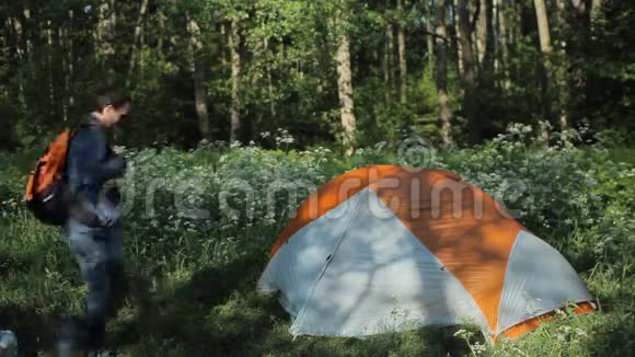 那个人在帐篷附近卸下一个背包想找点东西清晨在森林里视频的预览图