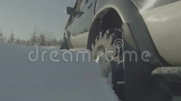 冬天驾驶越野车在森林道路上雪很多汽车卡在树林里特写视频的预览图