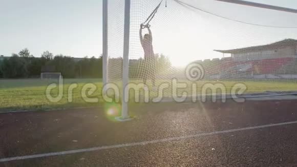 漂亮的健身女孩在体育场训练一个年轻的运动员在足球球门中在球场上绕圈子视频的预览图