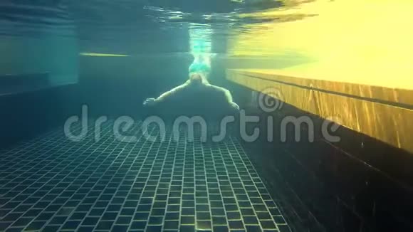 快乐开朗的年轻女子在蓝色游泳套房游泳池水下景观操作摄像机视频的预览图