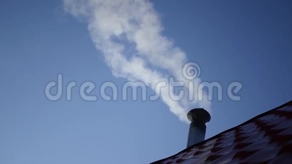 从房子的烟囱里冒出来的烟上面有红色的屋顶瓷砖背景是纯净明亮的蓝天慢动作1920x1080视频的预览图