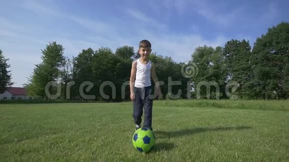 男孩在足球场上踢足球慢动作视频的预览图