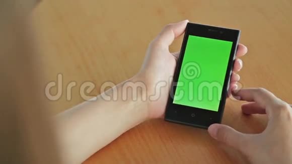 在咖啡馆里看着绿屏智能手机的女人视频的预览图