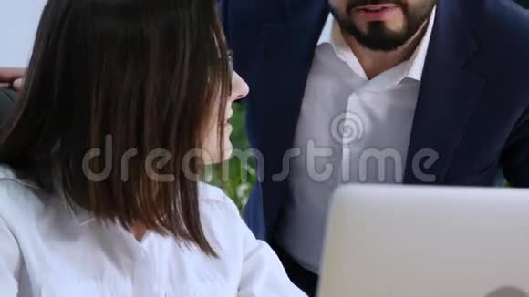 漂亮的女孩在办公室的笔记本电脑上咨询男人关于这个项目的情况它在屏幕上显示了你的手指视频的预览图