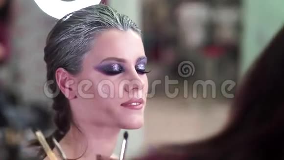化妆师将化妆应用于一个有吸引力的年轻模特的照片会议眼睛视频的预览图