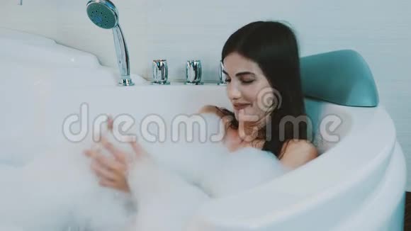 快乐的黑发女孩享受充满泡沫的浴缸按摩浴缸浴缸别紧张休息视频的预览图