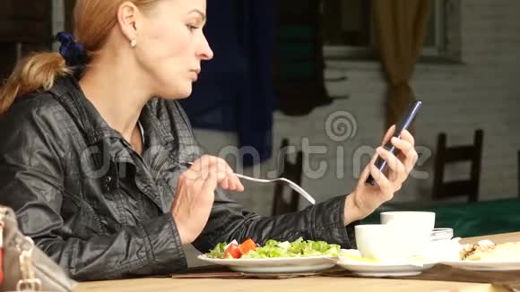 女商人在户外咖啡馆吃沙拉女孩吃绿色美味的食物并检查电子邮件在你的手机慢动作视频的预览图