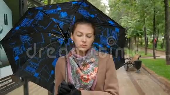 年轻悲伤的女人正在公园里的雨中散步视频的预览图