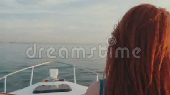 穿绿松石衣服的女孩驾驶摩托艇美丽的日落司机视频的预览图