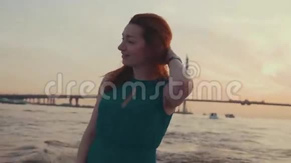 穿绿松石衣服的年轻女孩跪在摩托艇上日落跳舞乐趣视频的预览图