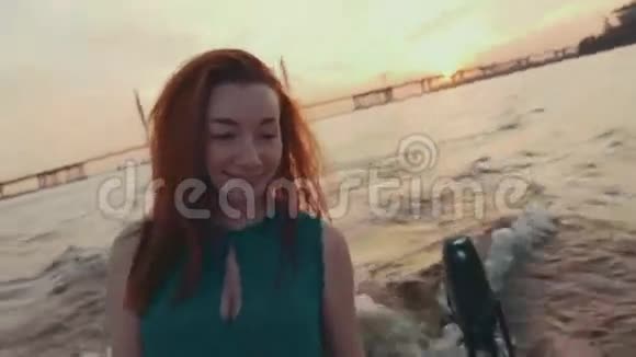 穿着绿松石衣服的年轻女孩在帆船上摸头发日落河流视频的预览图