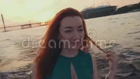 穿着绿松石衣服的年轻女孩在摩托艇上摸头发看日落浪漫浪漫视频的预览图