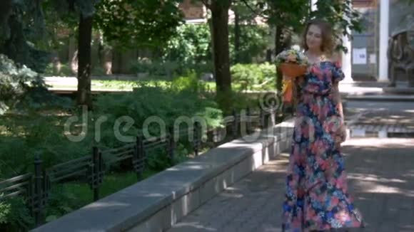 年轻的女人穿着一件漂亮的裙子走在公园里带着一束花特写视频的预览图