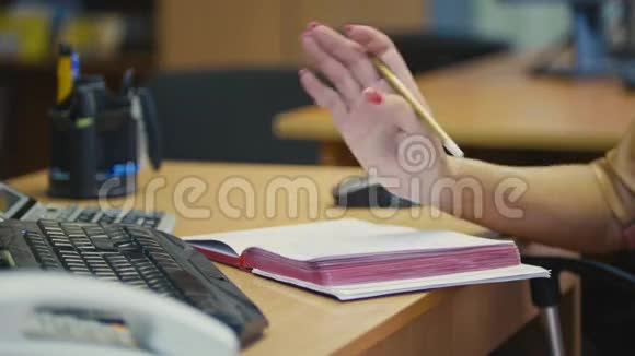 妇女办公室经理在电话交谈时的手势在记事本上记笔记关闭视频的预览图