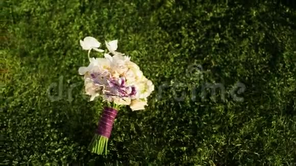 在一片美丽的绿色草坪上结婚的玫瑰和兰花束视频的预览图