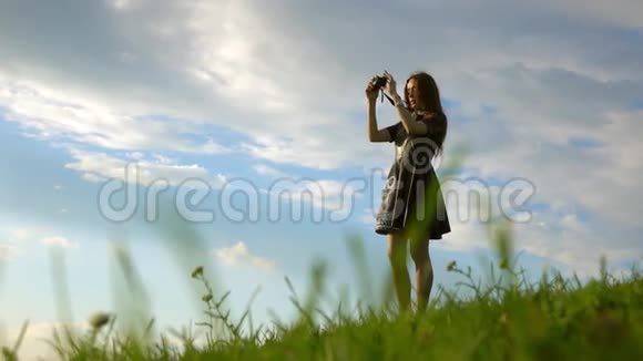 美丽的黑发女孩站在山上用她的紧凑型相机拍照业余视频的预览图