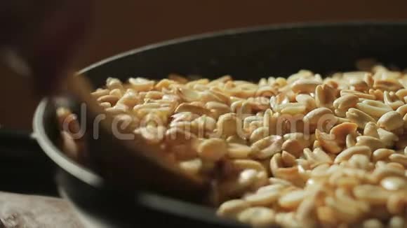 去皮的花生在平底锅里煎用勺子搅拌坚果视频的预览图