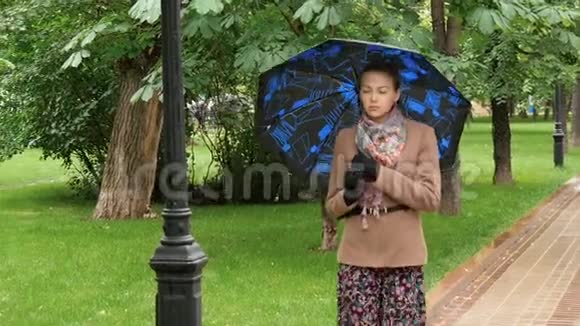 年轻悲伤的女人正在公园里的雨中散步视频的预览图