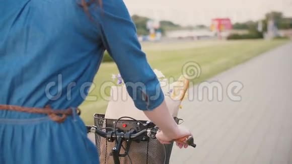 女孩的手放在自行车的车把上花和面包放在篮子里在城市里骑自行车慢节奏稳定的射击视频的预览图