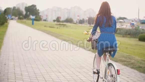 一个女孩骑着花篮在马路上骑着自行车在城市里探险慢的稳定的镜头视频的预览图