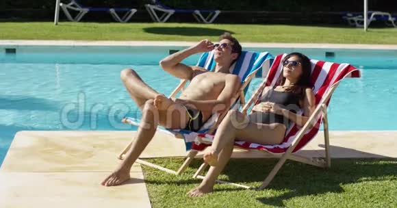年轻夫妇在度假游泳池放松视频的预览图