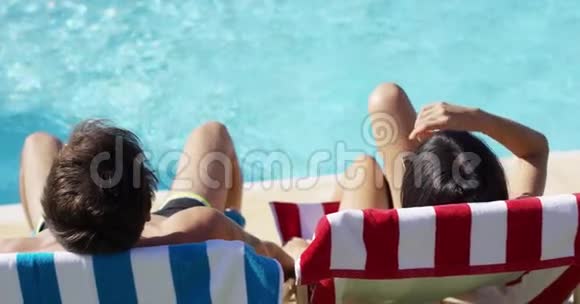 一对情侣在泳池边的彩色躺椅上放松视频的预览图