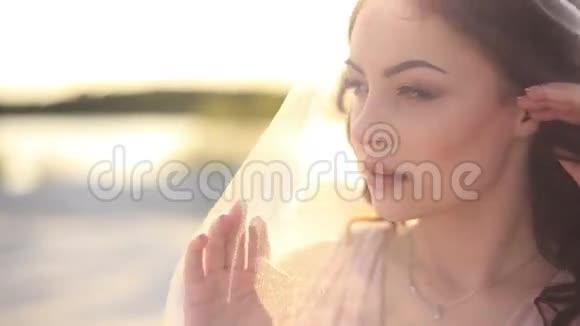 性感的年轻黑发女人用面纱遮住她的脸特写镜头夏默阳光海滩背景视频的预览图