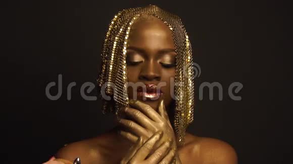 神秘神奇的非洲裔美国女性模特金色光泽的化妆和头饰摆姿势相机高级时装视频的预览图
