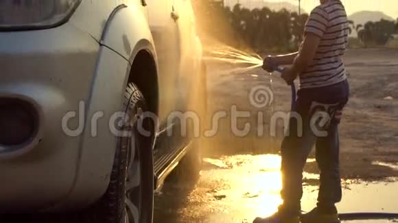 快乐亚洲小孩用喷水洗车带日落和耀斑的慢动作拍摄视频的预览图