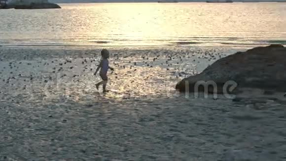 小女孩在日落的低潮时沿着湿沙滩奔跑视频的预览图